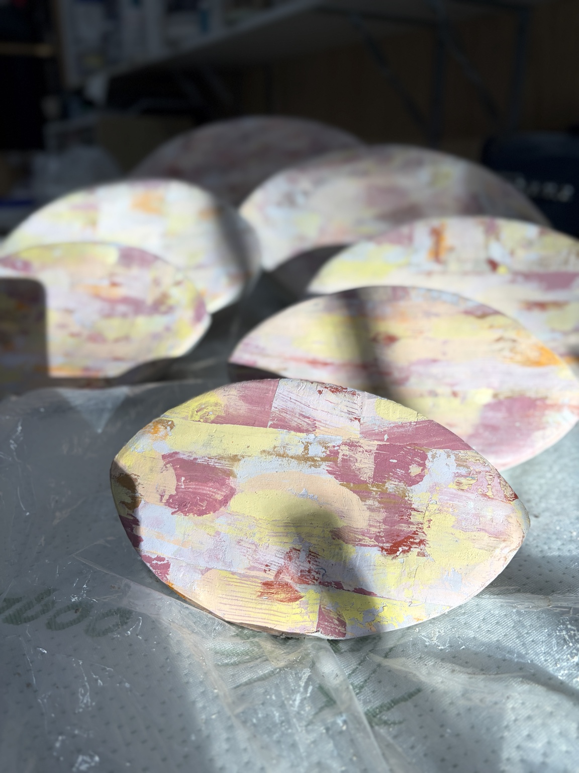 Close view of ceramic pod forms covered in layered pastel monoprint marks