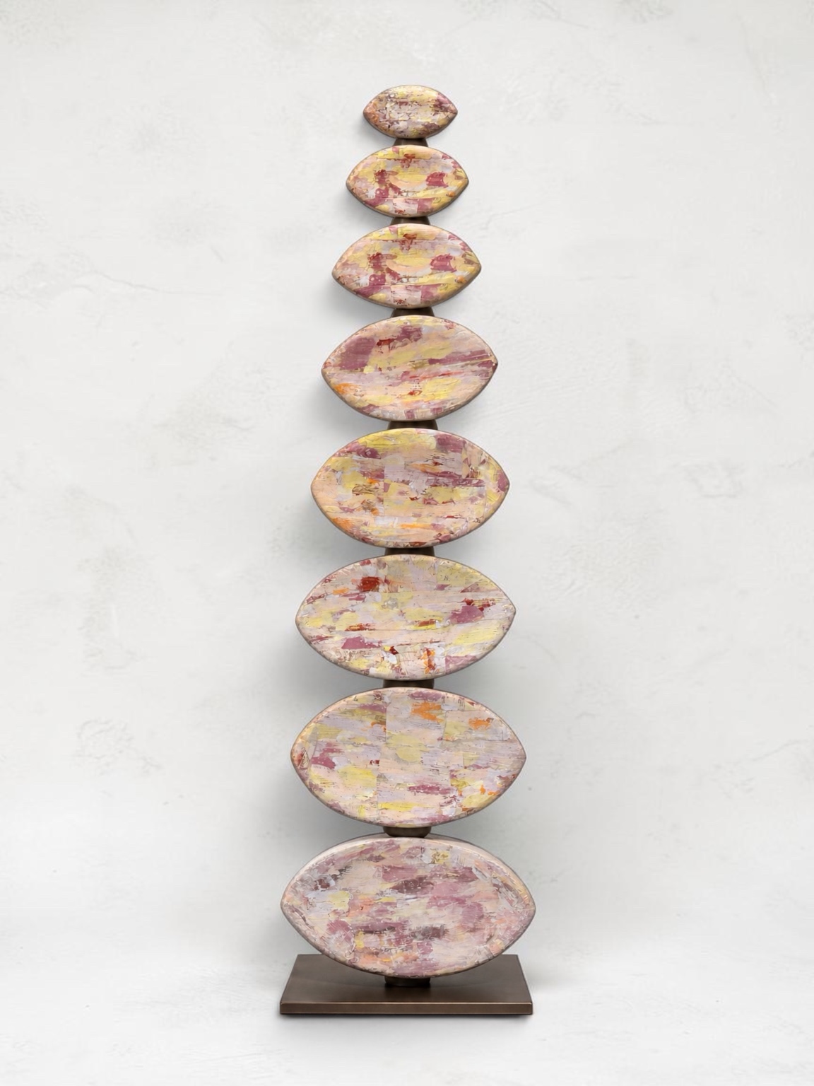 Holding Seed, a tall totem of eight pastel monoprinted ceramic seed-pod forms
